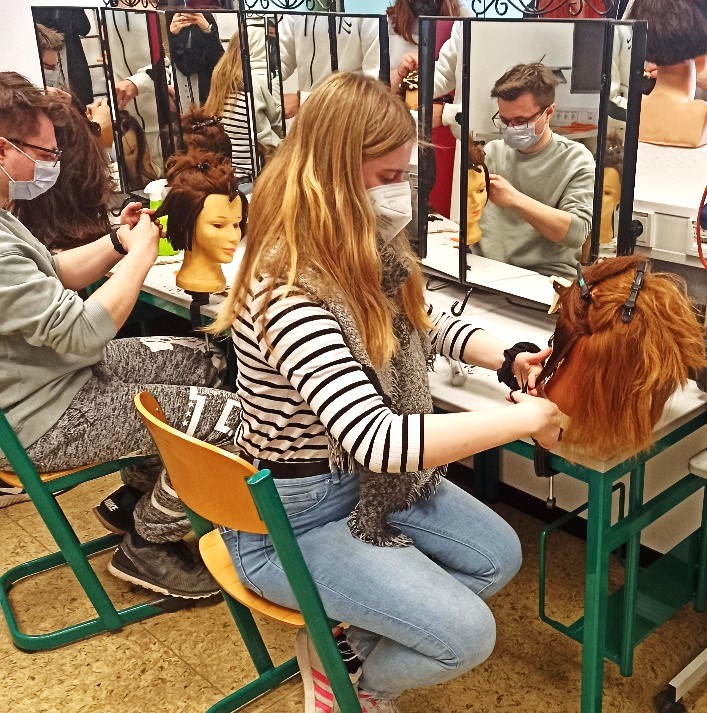 Schülerin bei der Arbeit am Hinterkopf einer Friseurpuppe